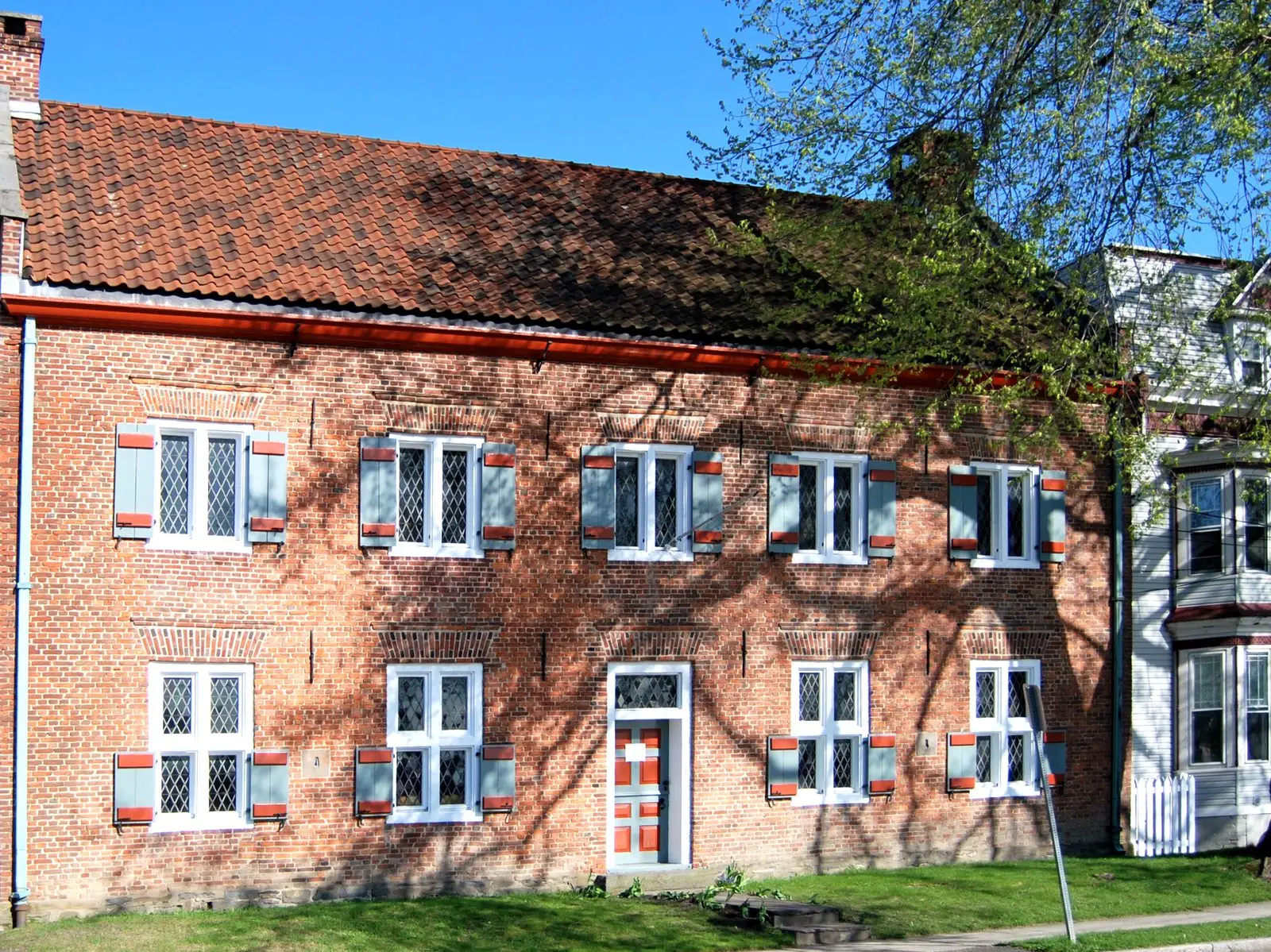 Early Dutch brick manor house with a red tile roof and shuttered windows in Rensselaer